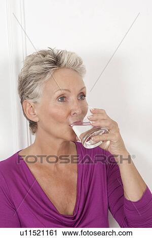 Stock Image - Older woman drinking glass of water. Fotosearch