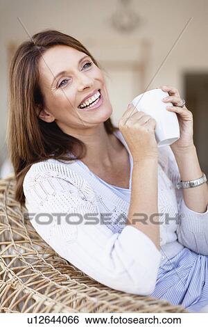 Stock Photograph - Older woman having coffee in armchair. Fotosearch