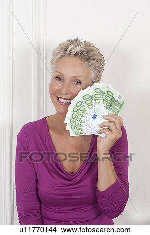 Older woman holding stack of Euros View Large Photo Image Picture - Older woman holding stack of Euros. Fotosearch