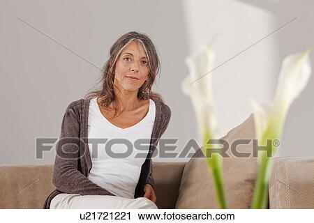 Stock Image - Older woman relaxing on sofa. Fotosearch