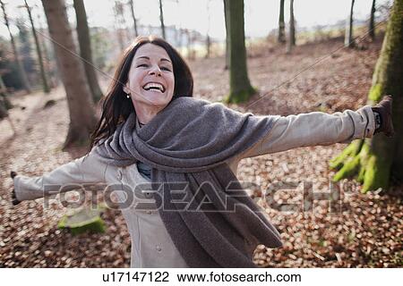 Stock Image - Older woman walking in forest. Fotosearch