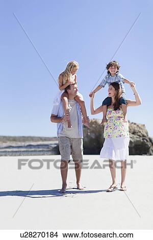 Parents carrying children on shoulders View Large Photo Image Picture - Parents carrying children on shoulders. Fotosearch