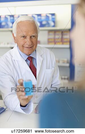 Pharmacist offering drugs at counter View Large Photo Image Stock Image - Pharmacist offering drugs at counter. Fotosearch