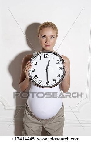 Pregnant woman holding clock View Large Photo Image Stock Photography - Pregnant woman holding clock. Fotosearch
