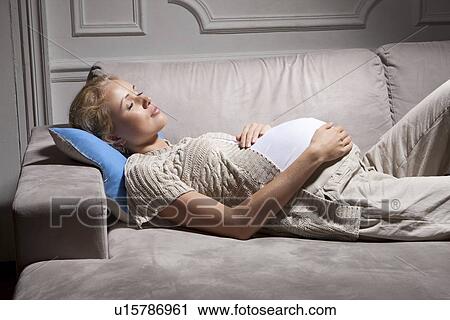 Stock Image - Pregnant woman sleeping on sofa. Fotosearch