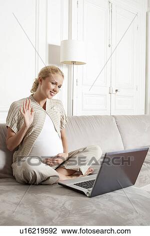 Stock Image - Pregnant woman using video chat. Fotosearch