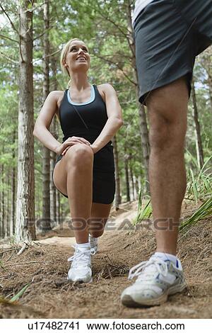Stock Image - Runners stretching on dirt path. Fotosearch