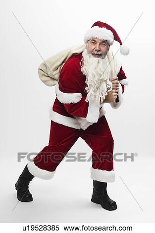 Santa carrying sack of Christmas gifts View Large Photo Image Stock Photography - Santa carrying sack of Christmas gifts. Fotosearch