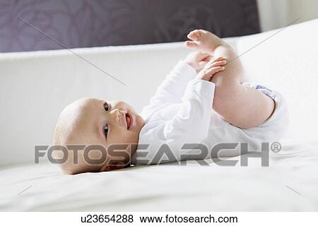 Smiling baby playing on bed View Large Photo Image Stock Photo - Smiling baby playing on bed. Fotosearch