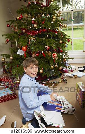 Stock Photograph - Smiling boy opening Christmas gift. Fotosearch