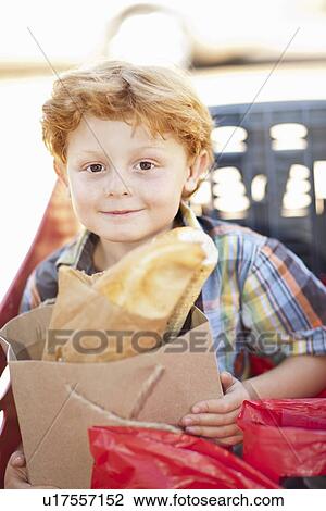 Stock Image - Smiling boy sitting in shopping cart. Fotosearch