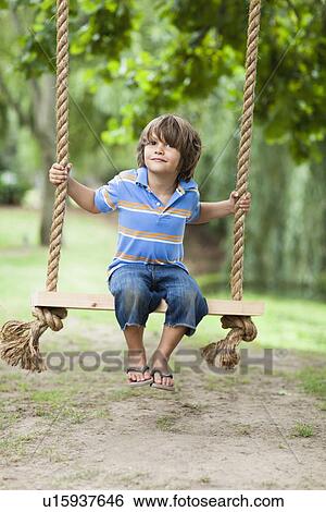 Smiling boy sitting in tree swing View Large Photo Image Stock Photograph - Smiling boy sitting in tree swing. Fotosearch