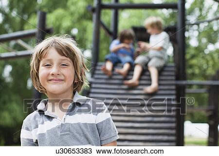 Stock Image - Smiling boy standing in playground. Fotosearch