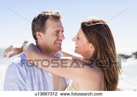 Stock Image - Smiling couple hugging outdoors. Fotosearch
