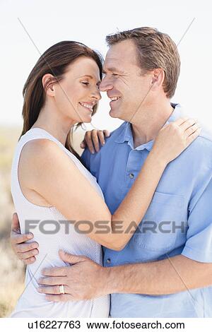 Stock Image - Smiling couple hugging outdoors. Fotosearch