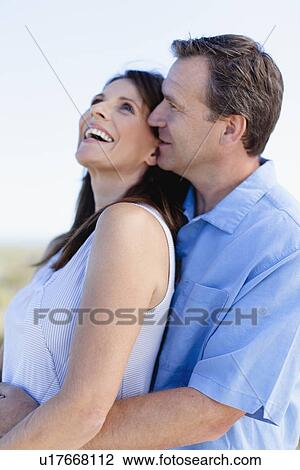 Stock Image - Smiling couple hugging outdoors. Fotosearch