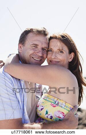 Stock Image - Smiling couple hugging outdoors. Fotosearch