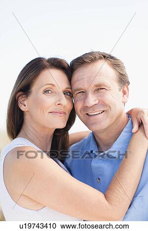 Stock Image - Smiling couple hugging outdoors. Fotosearch