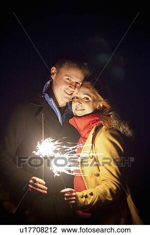 Stock Image - Smiling couple playing with sparklers. Fotosearch