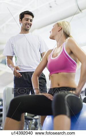 Smiling couple talking in gym View Large Photo Image Stock Image - Smiling couple talking in gym. Fotosearch