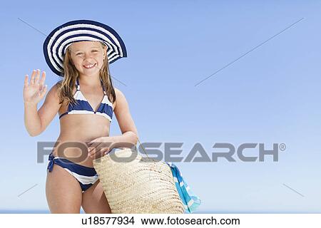 Picture - Smiling girl carrying straw bag outdoors. Fotosearch