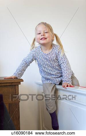 Picture - Smiling girl climbing barrier indoors. Fotosearch