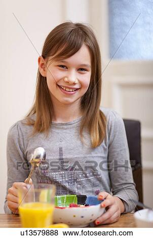 Stock Photo - Smiling girl eating at table. Fotosearch