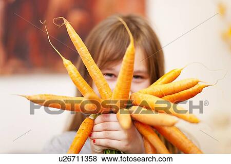 Smiling girl holding bunch of carrots View Large Photo Image Stock Photo - Smiling girl holding bunch of carrots. Fotosearch
