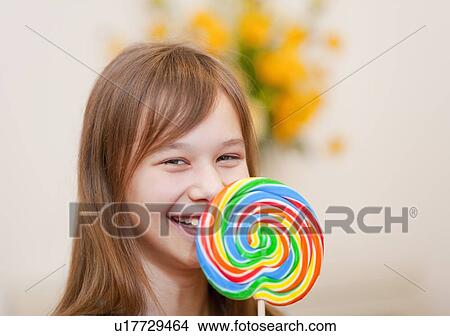 Picture - Smiling girl holding lollipop. Fotosearch