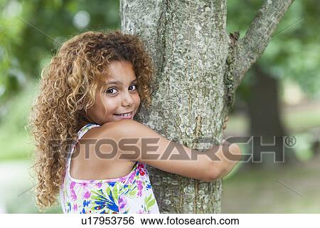 Smiling girl hugging tree outdoors View Large Photo Image Stock Photograph - Smiling girl hugging tree outdoors. Fotosearch