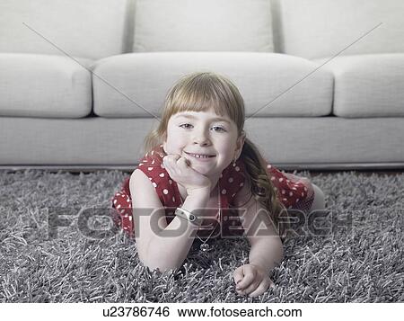 Stock Photograph - Smiling girl laying on rug. Fotosearch