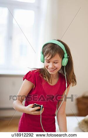 Stock Image - Smiling girl listening to mp3 player. Fotosearch
