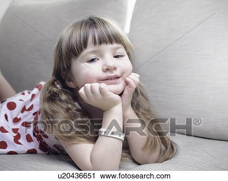 Stock Image - Smiling girl relaxing on sofa. Fotosearch