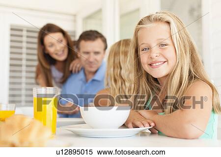 Smiling girl sitting at breakfast table View Large Photo Image Stock Photography - Smiling girl sitting at breakfast table. Fotosearch
