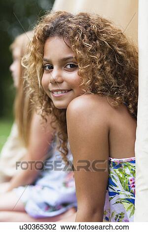 Stock Image - Smiling girl sitting in tent outdoors. Fotosearch