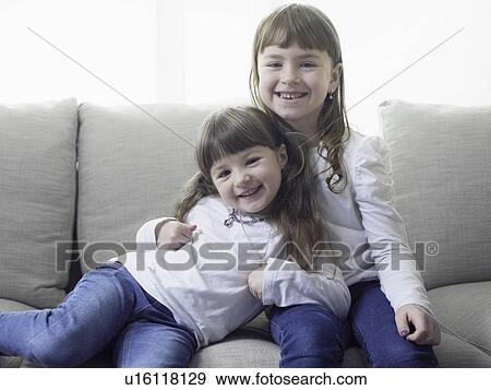 Smiling girls sitting on sofa together View Large Photo Image Stock Photo - Smiling girls sitting on sofa together. Fotosearch