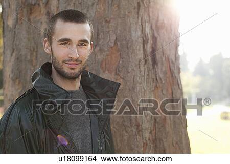 Picture - Smiling man standing in park. Fotosearch