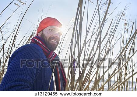 Stock Photography - Smiling man standing in tall reeds. Fotosearch