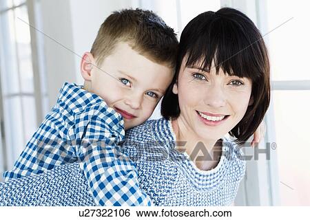 Stock Photograph - Smiling mother carrying son piggyback. Fotosearch