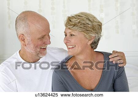 Stock Photography - Smiling older couple sitting on bed. Fotosearch