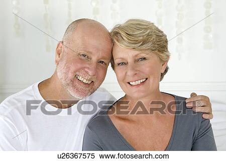 Smiling older couple sitting on bed View Large Photo Image Stock Photography - Smiling older couple sitting on bed. Fotosearch