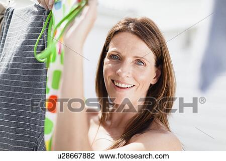 Stock Image - Smiling woman hanging laundry. Fotosearch