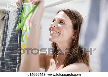 Smiling woman hanging laundry View Large Photo Image Stock Photo - Smiling woman hanging laundry. Fotosearch