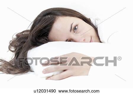 Stock Image - Smiling woman relaxing in bed. Fotosearch