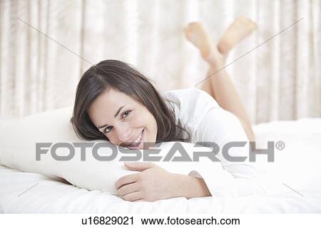 Smiling woman relaxing in bed View Large Photo Image Stock Image - Smiling woman relaxing in bed. Fotosearch