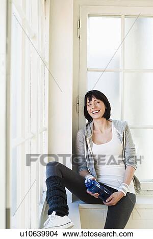 Picture - Smiling woman sitting in windowsill. Fotosearch