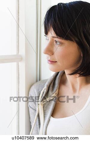 Stock Photo - Smiling woman standing by window. Fotosearch