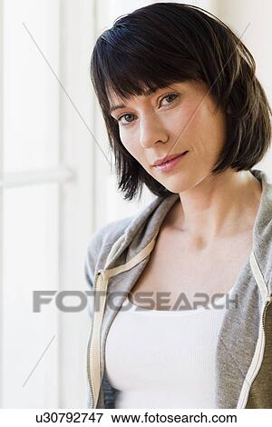 Smiling woman standing by window View Large Photo Image Stock Photo - Smiling woman standing by window. Fotosearch