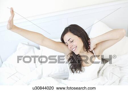 Smiling woman stretching in bed View Large Photo Image Stock Image - Smiling woman stretching in bed. Fotosearch