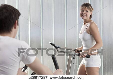 Stock Photo - Smiling woman using exercise machine. Fotosearch